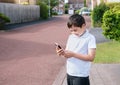 Portrait schoolboy using smartphone typing text messages, Happy kid standing outdoor using cellphone chatting with friends,Child