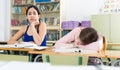 Portrait schoolgirl and her girlfriend who is sleeping on the desk Royalty Free Stock Photo