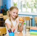 Portrait schoolgirl looking at camera while having lunch during