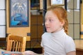 Portrait of a schoolgirl with red hair sitting at a Desk