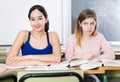 Portrait schoolgirl who is envying her successful girlfriend at the desk