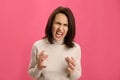 Portrait of screaming woman filled with hate on pink