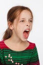 Portrait of a screaming 8-year-old girl in a sweater in crimson and green stripes