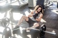 Portrait of screaming young adult man athlete with long curly hair working out in gym, sitting on floor and have strong hurt