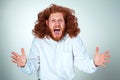 Portrait of screaming young man with long red hair and shocked facial expression on gray background Royalty Free Stock Photo