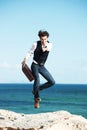 Portrait, seaside and jump with man, briefcase and excited with happiness, vacation and business. Happy person, employee Royalty Free Stock Photo