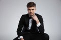 portrait of seated young businessman in tuxedo fixing his bowtie Royalty Free Stock Photo