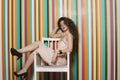 Portrait of a seductive young woman sitting on chair against colorful striped background Royalty Free Stock Photo