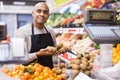 Portrait of seller in an apron with kiwi near a supermarket counter