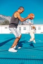 Portrait of senior adult turkish cypriot man playing basketball with a small cute jumping dog jack russel terrier on Royalty Free Stock Photo