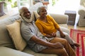 Portrait of senior african american couple sitting on sofa holding hands looking at camera smiling Royalty Free Stock Photo
