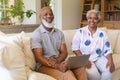 Portrait of senior african american couple sitting on sofa looking at camera and smiling Royalty Free Stock Photo