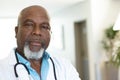 Portrait of senior african american male doctor in hospital corridor, with copy space Royalty Free Stock Photo