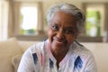 Portrait of senior african american woman sitting on sofa looking at camera and smiling Royalty Free Stock Photo