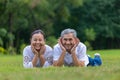 Portrait of senior Asian couple lying down on the grass in the public park looking at the camera with good mental health for Royalty Free Stock Photo