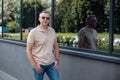 Portrait of senior brutal man in sunglasses walking with hands in pockets of jeans along modern office building Royalty Free Stock Photo