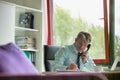 Mature businessman writing notes while talking on telephone in office Royalty Free Stock Photo