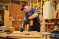 Portrait of a senior carpenter with drilling instrument working in the carpentry workshop to make a piece of furniture