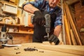 Portrait of a senior carpenter with drilling instrument working in the carpentry workshop to make a piece of furniture