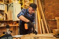 Portrait of a senior carpenter with drilling instrument working in the carpentry workshop to make a piece of furniture