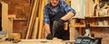 Portrait of a senior carpenter with drilling instrument working in the carpentry workshop to make a piece of furniture