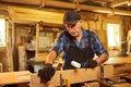 Portrait of a senior carpenter in uniform gluing wooden bars with hand pressures at the carpentry manufacturing