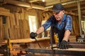 Portrait of a senior carpenter in uniform gluing wooden bars with hand pressures at the carpentry manufacturing