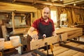 Portrait of a senior carpenter in uniform gluing wooden bars with hand pressures at the carpentry manufacturing