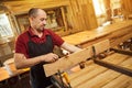 Portrait of a senior carpenter in uniform gluing wooden bars with hand pressures at the carpentry manufacturing Royalty Free Stock Photo