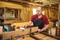 Portrait of a senior carpenter in uniform gluing wooden bars with hand pressures at the carpentry manufacturing