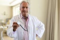 Portrait of senior caucasian male doctor holding stethoscope looking at camera Royalty Free Stock Photo