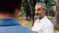 Portrait of a senior caucasian man giving advice and suggestion to his son while walking and discussion problem in the park, Royalty Free Stock Photo