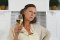 ortrait of senior caucasian woman in modern kitchen, holding glass of wine, looking to camera Royalty Free Stock Photo