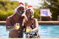 Portrait Of Senior Couple On Christmas Holiday In Swimming Pool Wearing Santa Hats Royalty Free Stock Photo