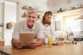 Portrait, senior couple and cooking with tablet together in a modern kitchen of the home. Happy, retirement and elderly