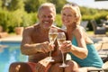 Portrait Of Senior Couple On Holiday In Swimming Costumes Drinking Champagne By Hotel Swimming Pool Royalty Free Stock Photo