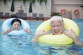 Portrait of senior couple relaxing in the pool with inflatable tubes Royalty Free Stock Photo