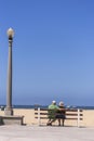 Portrait, Senior couple sitting on boardwalk bench, Santa Monica, CA, USA Royalty Free Stock Photo