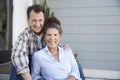 Portrait Of Senior Couple Sitting Outside Grey Clapboard House Royalty Free Stock Photo