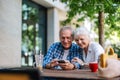 Senior couple sitting at a table in a cafe and using mobile phone Royalty Free Stock Photo