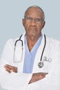 Portrait of a senior doctor with arms crossed over light blue background Royalty Free Stock Photo