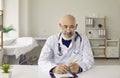 Portrait of senior doctor sitting at desk during telemedicine video consultation