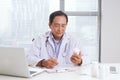 Portrait of senior doctor sitting at his desk in medical office Royalty Free Stock Photo