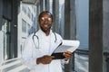 Portrait of senior doctor wearing glasses African American man looking at camera and smiling outside modern clinic Royalty Free Stock Photo