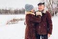 Portrait of senior family couple walking outdoors during snowy winter weather. Mature people hugging Royalty Free Stock Photo