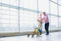 Senior farmer pushing forklift while talking to young female farmer holding clipboard at greenhouse Royalty Free Stock Photo