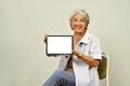Portrait of senior female doctor showing digital tablet with blank mockup screen for medical healthcare tech website Royalty Free Stock Photo