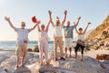 Portrait Of Senior Friends Standing On Rocks By Sea On Summer Group Vacation With Arms Outstretched Royalty Free Stock Photo