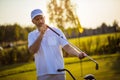 Senior golfer standing on court and holding stick