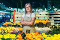 Portrait of a senior gray-haired woman of a supermarket worker, worker spreads fruit with crossed arms smiles and looks at camera Royalty Free Stock Photo